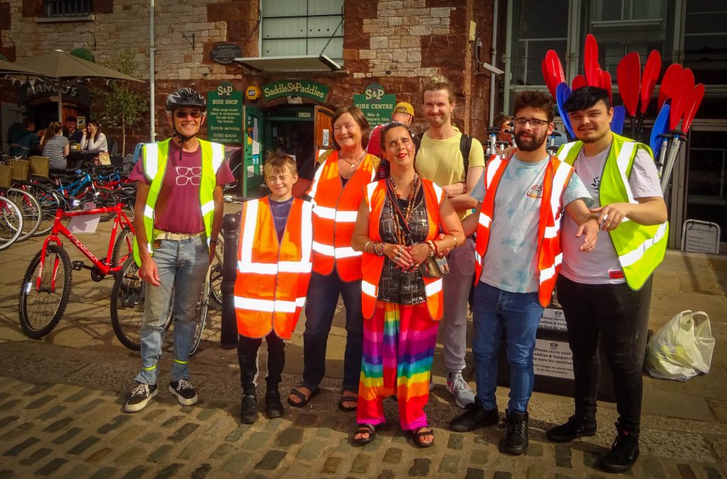 A photos showing Dawn with her supporters in high-vis jackets, outside the Bike hire shop
