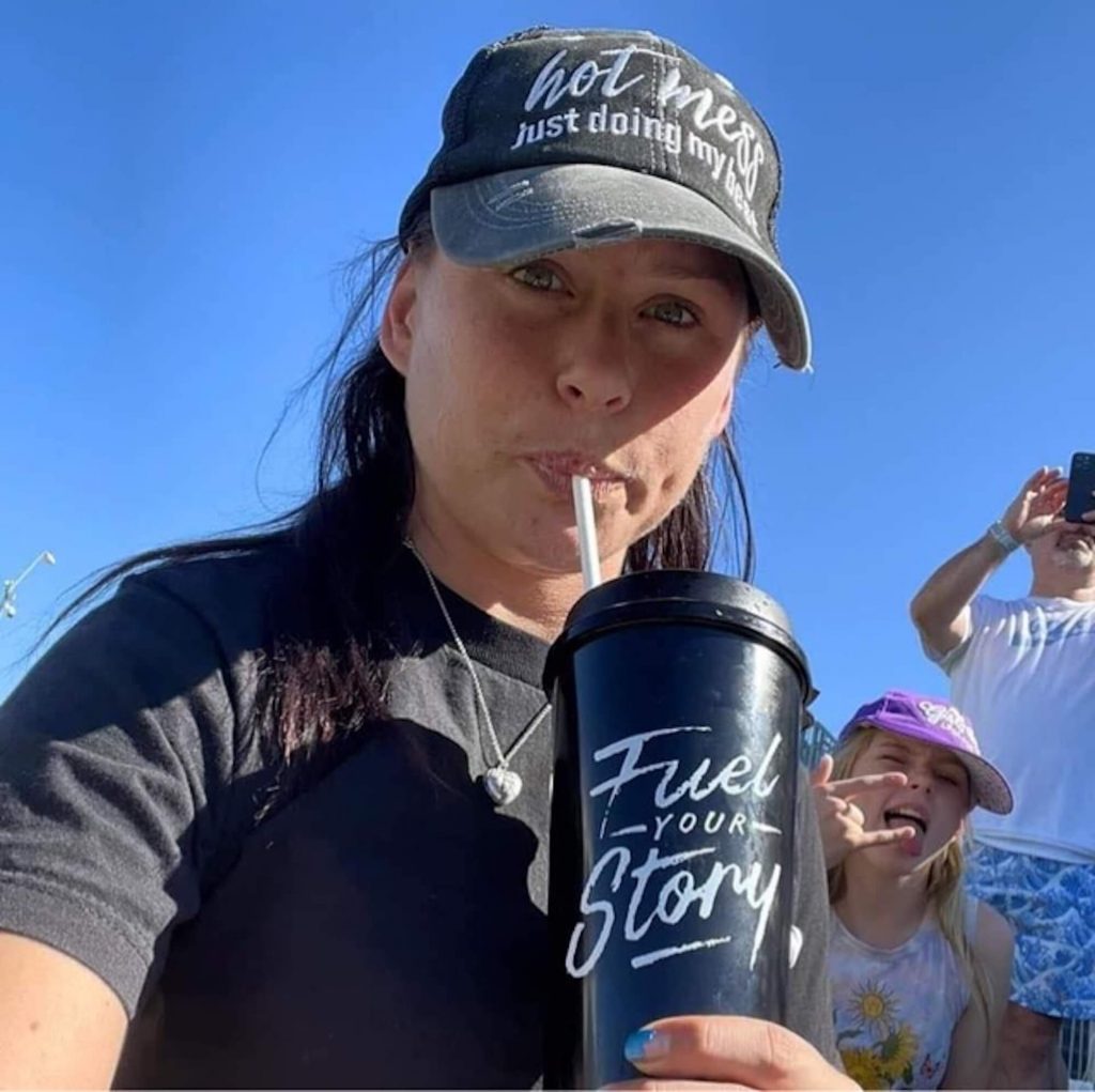 Photo showing Valerie wearing a baseball cap and drinking out of a cup with a straw and the message 'Fuel your story', with a young girl in the background.
