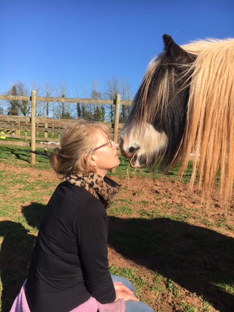 Photo of a person nose to nose with a horse.